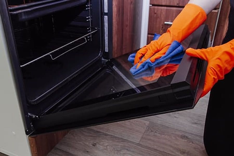 Cleaner in protective gloves deep cleaning an oven interior in a Jacksonville home