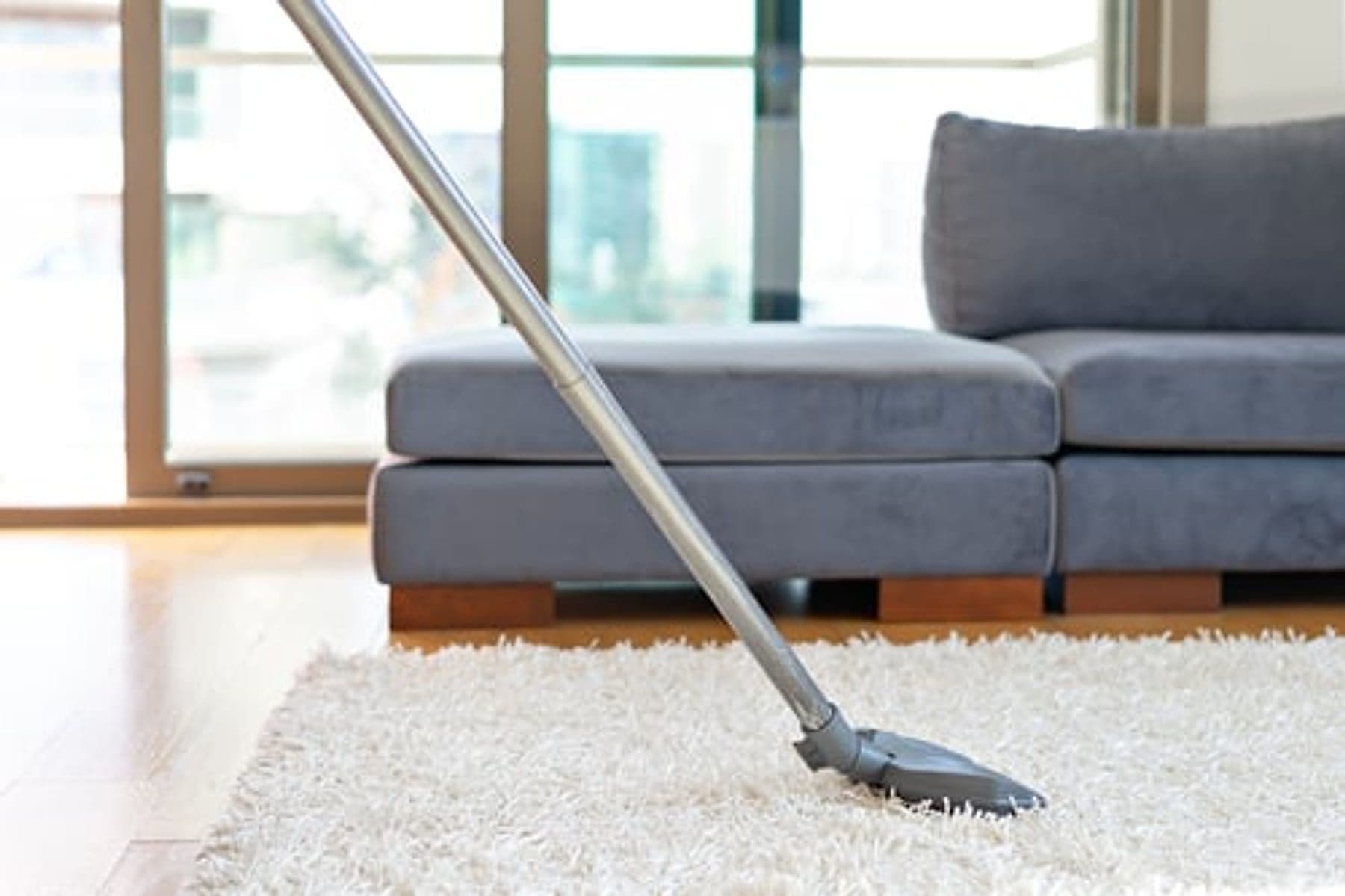 Vacuuming a light rug in a bright, tidy Jacksonville living room