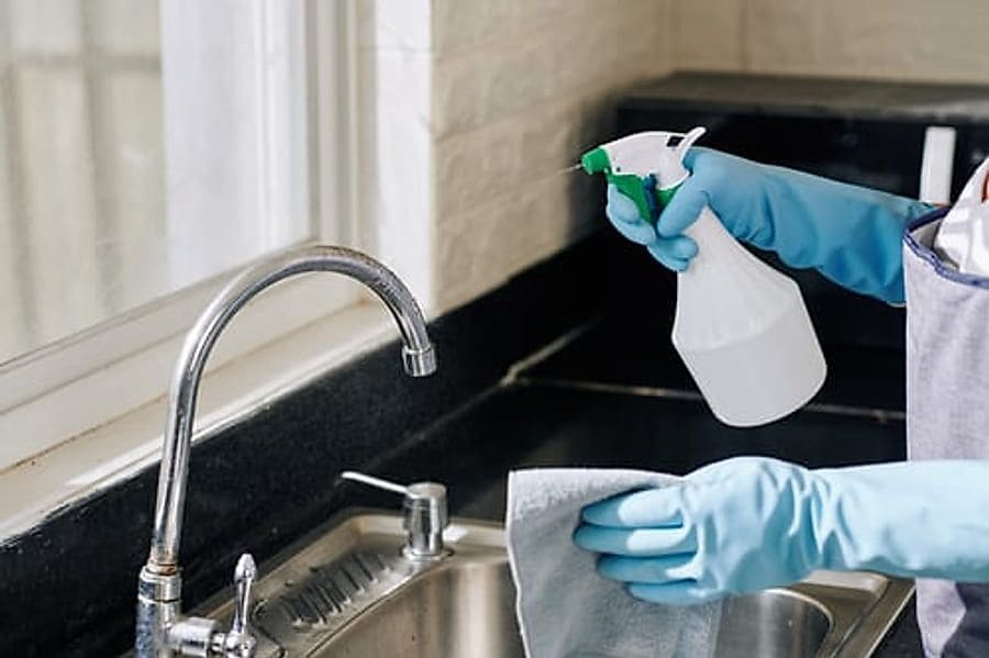 Cleaner disinfecting a dark kitchen countertop during a deep cleaning in Jacksonville, FL